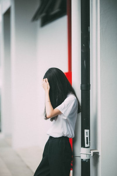 女人倚靠在白色的水泥墙上